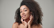 © Anatoly Repin - Beauty and healthcare concept - beautiful African American woman with curly afro hairstyle and clean, healthy skin touching face with hand, doing facial massage, posing and looking at camera