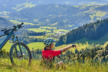 Wall Mural - nice active senior woman riding her electric mountain bike at Mount Huendle in Oberstaufen, Allgaeu Alps , Bavaria, Germany