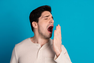 Sticker - Portrait of nice young man cover mouth yawn empty space wear pajama isolated on blue color background