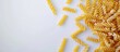 © Ilgun - Raw fusilli pasta on a white backdrop with copy space image Dry macaroni displayed flat in a visually unhealthy manner