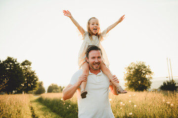 Wall Mural - happy child girl and father are playing in field.