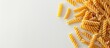 © Ilgun - Raw fusilli pasta on a white backdrop with copy space image Dry macaroni displayed flat in a visually unhealthy manner