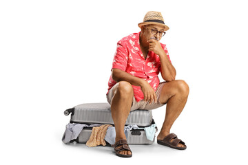 Poster - Worried mature tourist sitting on a packed suitcase with messy clothes