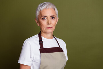 Wall Mural - Photo of serious confident woman wear apron serving coffee empty space isolated khaki color background