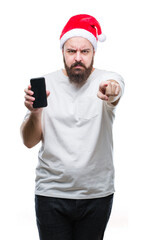 Poster - Young caucasian man wearing christmas hat showing smartphone screen over isolated background pointing with finger to the camera and to you, hand sign, positive and confident gesture from the front