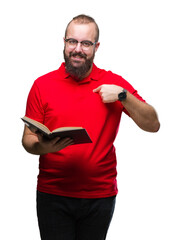 Canvas Print - Young hipster man wearing glasses and reading a book over isolated background with surprise face pointing finger to himself