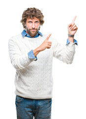 Canvas Print - Handsome hispanic man model wearing winter sweater over isolated background smiling and looking at the camera pointing with two hands and fingers to the side.