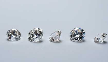 Five round cut diamonds of different sizes are arranged in a line on a white background