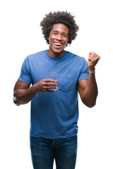 Canvas Print - Afro american man drinking glass of water over isolated background screaming proud and celebrating victory and success very excited, cheering emotion