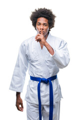 Canvas Print - Afro american man wearing karate kimono over isolated background asking to be quiet with finger on lips. Silence and secret concept.