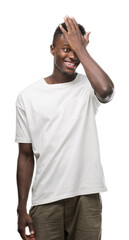 Canvas Print - Young african american man wearing white t-shirt surprised with hand on head for mistake, remember error. Forgot, bad memory concept.