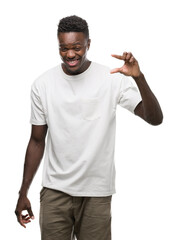 Sticker - Young african american man wearing white t-shirt smiling and confident gesturing with hand doing size sign with fingers while looking and the camera. Measure concept.