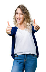 Wall Mural - Beautiful young blonde woman over isolated background approving doing positive gesture with hand, thumbs up smiling and happy for success. Looking at the camera, winner gesture.