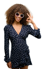 Wall Mural - African american woman with sunglasses and summer dress doing ok sign with fingers, excellent symbol