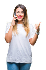 Sticker - Young beautiful woman speaking calling using smartphone over isolated background pointing and showing with thumb up to the side with happy face smiling