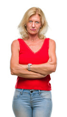 Sticker - Middle age blonde woman over isolated background skeptic and nervous, disapproving expression on face with crossed arms. Negative person.