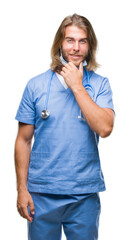 Sticker - Young handsome doctor man with long hair over isolated background looking confident at the camera with smile with crossed arms and hand raised on chin. Thinking positive.