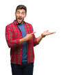 © Krakenimages.com - Young handsome man over isolated background amazed and smiling to the camera while presenting with hand and pointing with finger.