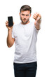 © Krakenimages.com - Young handsome man showing smartphone screen over isolated background with angry face, negative sign showing dislike with thumbs down, rejection concept