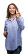 © Krakenimages.com - Young hispanic business woman smiling looking to the camera showing fingers doing victory sign. Number two.