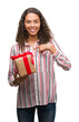 © Krakenimages.com - Young hispanic woman in love holding present with surprise face pointing finger to himself