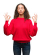 © Krakenimages.com - Young hispanic woman wearing red sweater relax and smiling with eyes closed doing meditation gesture with fingers. Yoga concept.
