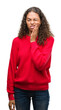 © Krakenimages.com - Young hispanic woman wearing red sweater touching mouth with hand with painful expression because of toothache or dental illness on teeth. Dentist concept.