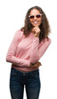 © Krakenimages.com - Beautiful young hispanic woman wearing sunglasses looking confident at the camera with smile with crossed arms and hand raised on chin. Thinking positive.