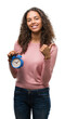 © Krakenimages.com - Young hispanic woman holding alarm clock happy with big smile doing ok sign, thumb up with fingers, excellent sign