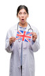© Krakenimages.com - Young hispanic doctor woman holding flag of united kingdom scared in shock with a surprise face, afraid and excited with fear expression