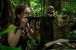 © Anastasia Knyazeva - A jungle explorer using binoculars to examine ancient ruins adorned with a skull.