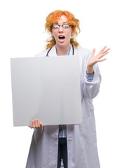 Canvas Print - Young redhead doctor woman holding banner very happy and excited, winner expression celebrating victory screaming with big smile and raised hands