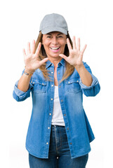 Sticker - Beautiful middle age woman wearing sport cap over isolated background showing and pointing up with fingers number ten while smiling confident and happy.