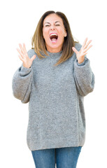 Wall Mural - Beautiful middle age woman wearing winter sweater over isolated background celebrating mad and crazy for success with arms raised and closed eyes screaming excited. Winner concept