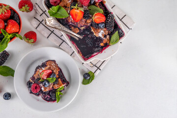 Wall Mural - Homemade sweet berry cobbler pie cake with various garden forest berries - strawberry, blackberry, blueberry, healthy summer dessert recipe in baking pan and plate, copy space