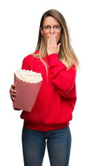 Canvas Print - Beautiful young woman eating popcorn cover mouth with hand shocked with shame for mistake, expression of fear, scared in silence, secret concept