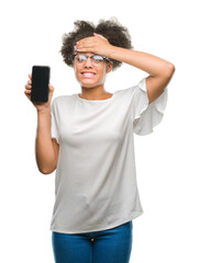 Canvas Print - Young beautiful afro american showing smartphone screen over isolated background stressed with hand on head, shocked with shame and surprise face, angry and frustrated. Fear and upset for mistake.