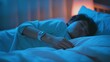 © Anna - A woman sleeps peacefully in bed with a smartwatch monitoring her sleep. The dimly lit room casts a soft blue glow