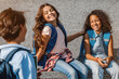 © InsideCreativeHouse - Group of elementary middle school children kids pupils classmates preteen boys and girls with backpack sitting on the steps and having fun spend time at recess break outdoors