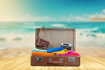 Wall Mural - Open travel suitcase with summer accessories at beach