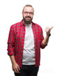 © Krakenimages.com - Young caucasian hipster man wearing glasses over isolated background smiling with happy face looking and pointing to the side with thumb up.