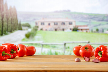 Wall Mural - Blurred beautiful Tuscany countryside houses and green fields and gardens background. Wooden table background with copy space for products and food and for montage objects display.