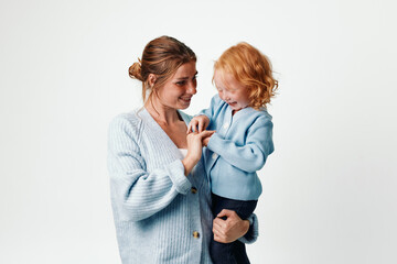 Wall Mural - Mother and daughter embracing in blue sweater on white background, family love and connection concept