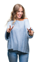 Wall Mural - Beautiful young blonde woman wearing winter sweater over isolated background smiling looking to the camera showing fingers doing victory sign. Number two.