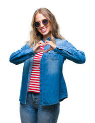 Poster - Beautiful young blonde woman wearing sunglasses over isolated background smiling in love showing heart symbol and shape with hands. Romantic concept.