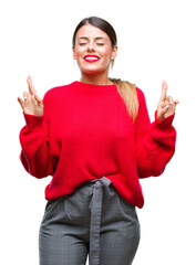 Canvas Print - Young beautiful business woman wearing winter sweater over isolated background smiling crossing fingers with hope and eyes closed. Luck and superstitious concept.