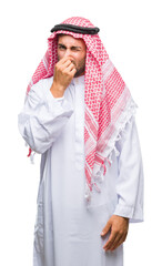 Poster - Young handsome man wearing keffiyeh over isolated background smelling something stinky and disgusting, intolerable smell, holding breath with fingers on nose. Bad smells concept.