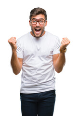 Wall Mural - Young handsome man wearing glasses over isolated background celebrating surprised and amazed for success with arms raised and open eyes. Winner concept.