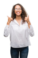 Sticker - Beautiful young hispanic woman success sign doing positive gesture with hand, thumbs up smiling and happy. Looking at the camera with cheerful expression, winner gesture.