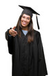 © Krakenimages.com - Young hispanic woman wearing graduated cap and uniform smiling friendly offering handshake as greeting and welcoming. Successful business.